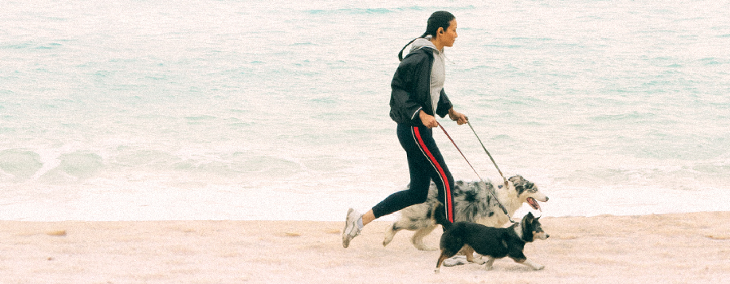 femme qui court avec ses chiens à la plage
