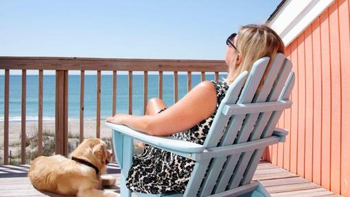 femme assise sur une chaise longue avec chien à ses côtés